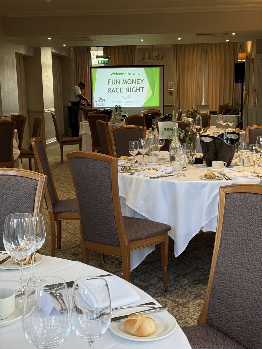 Hotel staff serving dinner while the race night screen waits in the background
