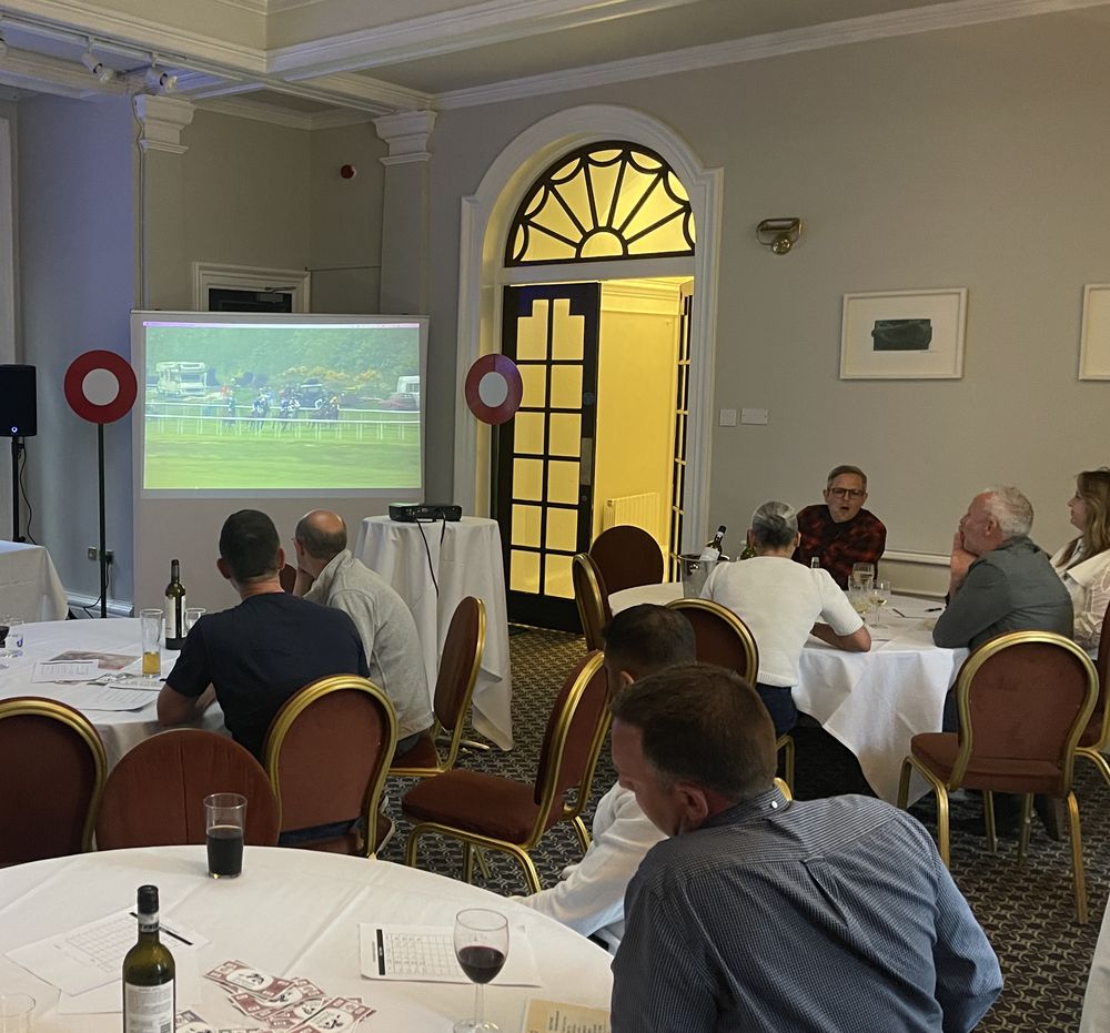 Hotel guests watching a race on the big screen between dinner courses