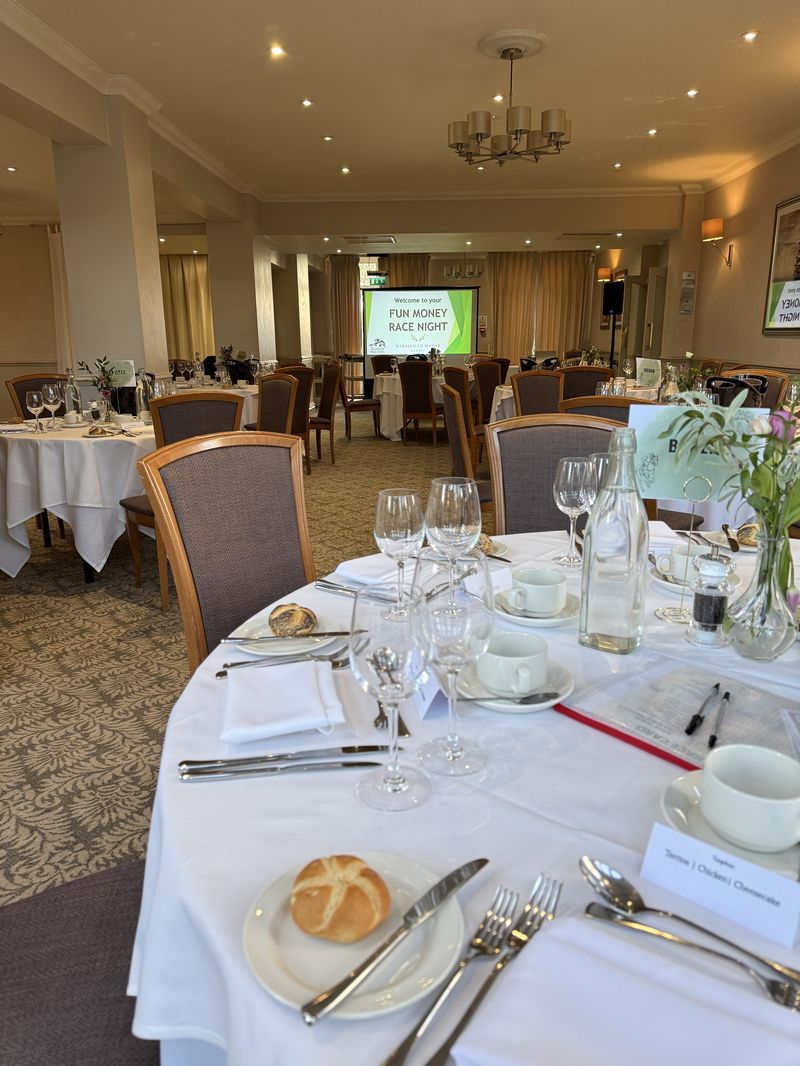 A hotel function room set for dinner with the race night screen ready